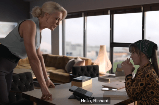 a woman standing over a phone as a teenager sits at a desk